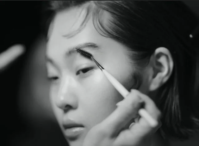 眉毛をブラシで整えている女性のモノクロのクローズアップ画像