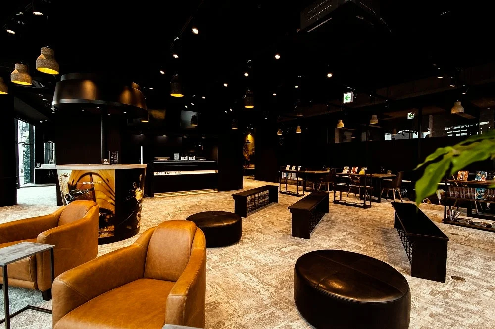 モダンで落ち着いた雰囲気のラウンジまたは受付エリアです。革張りの椅子やカウンター、「GORIILA FITNESS」のロゴが見え、フィットネス施設の共有スペースのようです。