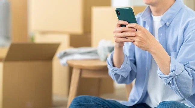 スマートフォンで引越し先を検索する男性