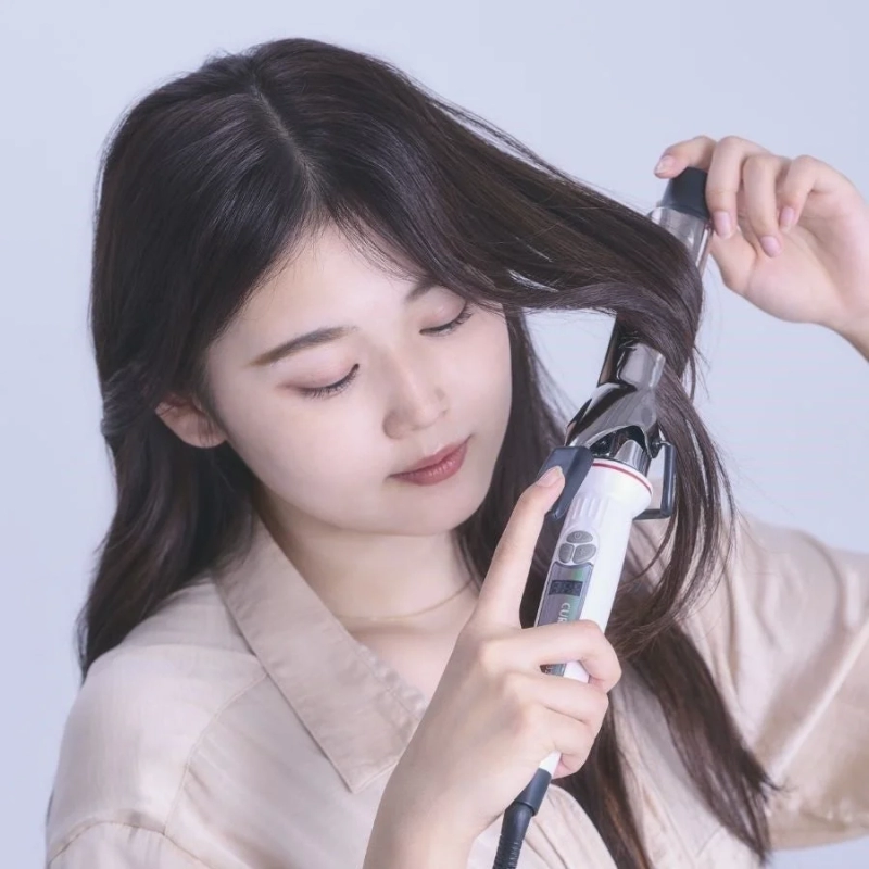 ヘアアイロンでスタイリングする女性