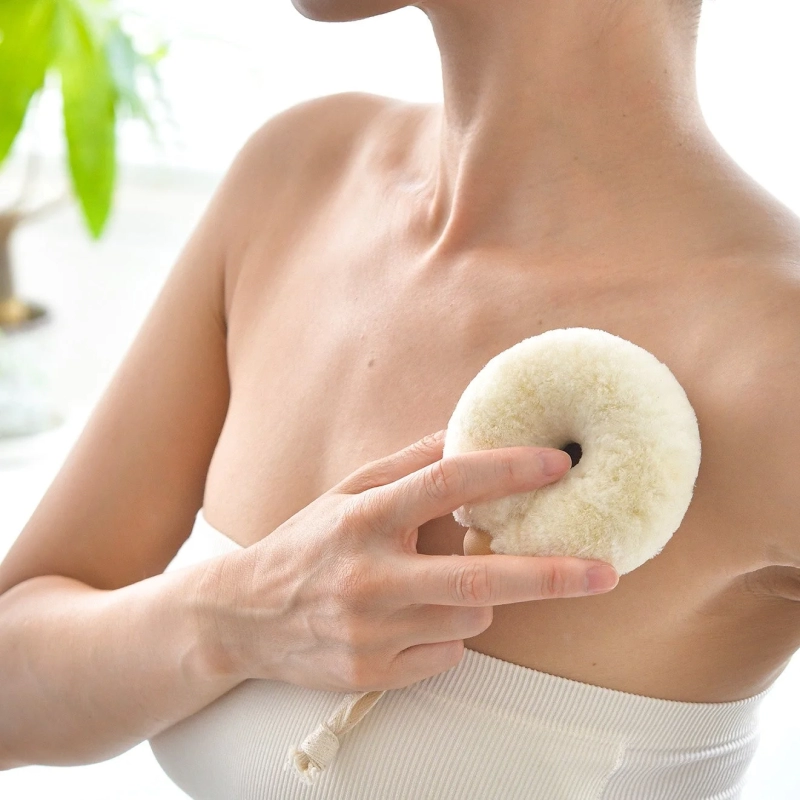 女性がボディケア用品を胸元に