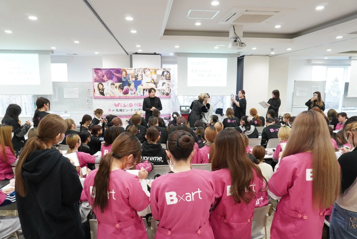 美容専門学校の授業風景、プロジェクターに「ベースメイク」「透明感UP」